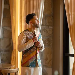 A quiet moment of anticipation. The groom's unique Nehru jacket, with its mix of prints and textures, is a testament to our belief in personalized, story-driven styling.