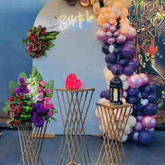 Perfect for a bridal shower or bachelorette party, this setup features a "Bride to be" neon sign, a modern balloon arch in rich colors, and elegant floral arrangements on geometric stands.