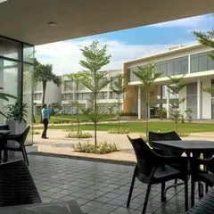 The dining area at the DRL Leadership Academy opens onto a landscaped central green. This seamless indoor-outdoor connection creates a pleasant, shaded space for informal activities that buzzes with life.