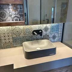 I often use patterned tiles to add character to a space. Here, a backsplash of colorful encaustic tiles provides a vibrant contrast to the modern concrete sink and minimalist black fixtures.
