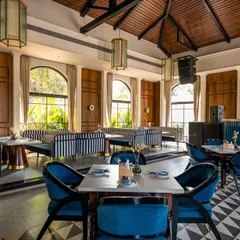 This shot captures the daytime ambiance at Vamos Experience, with natural light flooding in through the large arched windows. It highlights the airy, open feel of the space and its connection to the green outdoors.