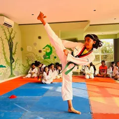 A student demonstrates a perfect high side kick, showcasing excellent form, balance, and flexibility.
