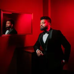 A dapper portrait of the groom in a classic tuxedo, captured with dramatic red lighting for a modern and stylish look. This showcases my creative approach to groom portraiture.