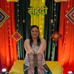 The groom's mom deserves her moment to shine too. Here she is, looking beautiful with her full-hand traditional mehendi against a vibrant backdrop.