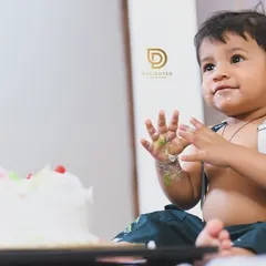 A classic cake smash moment! This little boy is all smiles with cake on his hands, perfectly capturing the fun of a first birthday.