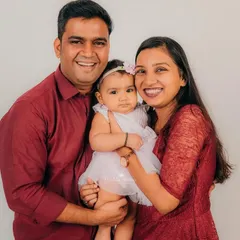 A bright and happy family portrait against a clean white background, showcasing the beautiful bond between parents and their eight-month-old baby girl.