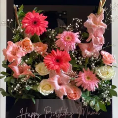 Modern elegance defined. This stunning arrangement features pink gerberas, gladioli, and soft roses in a sleek, black acrylic box with a personalized "Happy Birthday Mama" message, creating a truly luxurious statement piece.