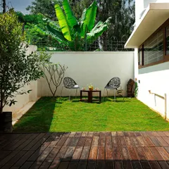 A simple yet effective outdoor space. The combination of a wooden deck and a small lawn creates a neat, functional backyard area, perfect for a quiet morning coffee.