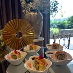 Freshly rolled sushi elegantly arranged on a mirrored table, reflecting the beautiful floral decor of the anniversary party.