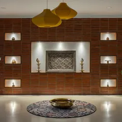 The journey into 'Vasudhalayah' begins with this foyer wall, clad in wire-cut bricks. Thoughtfully carved niches display cherished family heirlooms, creating a captivating and personal entrance.