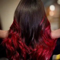 A perfect example of a bold red ombré on dark hair. I achieve this dramatic, fiery look by carefully blending the vibrant red into the natural base, creating a seamless fade that’s full of life and styled into beautiful, flowing waves.