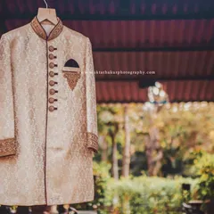 A detailed shot of the groom's wedding sherwani, focusing on the intricate buttons and embroidered pocket square.