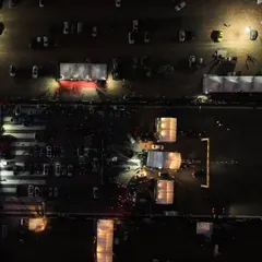 A bird's-eye view of the Vroom DragMeet at night. The entire venue is lit up, creating an electric atmosphere for the racers and the crowd.