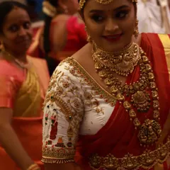 Seeing a bride's happiness is the best part of my work. Here is a client looking radiant on her wedding day in a custom white and red blouse, featuring intricate bride and groom figures embroidered on the sleeves.