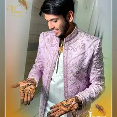 A happy groom proudly displays his custom mehndi, featuring designs that tell his love story.