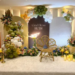 An elegant and modern blessing ceremony for baby Ruth. We combined an earthy palette of olive green and white balloons with lush floral arrangements, a stylish wicker peacock chair, and warm candlelight to create this serene and beautiful stage.