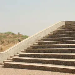 A side view of the amphitheater steps, showing their clean, geometric lines against the arid landscape. The design is both monumental and respectful of its natural setting.