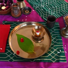 A detail of the festive tablescape, showing a brocade placemat in green, paired with traditional brass tableware.
