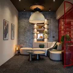 A wider view of the office lounge, separated from a workstation by a bold red mesh screen. This element adds an industrial touch and a pop of color while defining the space.