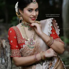 A beautiful, smiling bride is the best canvas. This look emphasizes a natural glow, with warm tones on the eyes and a classic red lip that complements the red and gold Kanjeevaram saree.
