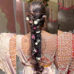 A beautiful fishtail braid with pops of pink and white flowers. This style is a favorite for pre-wedding ceremonies, offering a fresh and youthful take on the traditional braid.