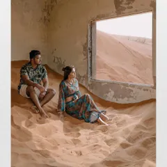 A quiet moment inside an abandoned structure, with sand pouring in through the window. This shot tells a story, with the couple looking out at the desert expanse, creating a cinematic and contemplative pre-wedding portrait.