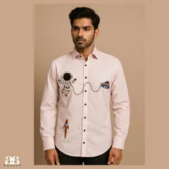 Showcasing a playful side, this light pink bespoke shirt is detailed with quirky, colorful hand embroidery of an astronaut and rocket. The design adds a touch of personality to a classic button-down, perfect for a smart casual look.