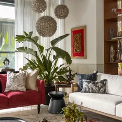 The living room was built around this bold red couch, which adds a vibrant pop of color and energy. It’s surrounded by the client's art, indoor plants, and a mix of textures to create a space that is full of life.