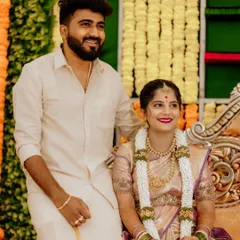 A candid moment captured during a baby shower celebration. The couple is dressed in beautiful traditional clothing, surrounded by festive decorations of marigold flowers, reflecting the joyous and cultural atmosphere of the event.