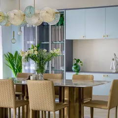 This dining room combines soft powder blue cabinetry with a striking marble-topped table and an artistic glass chandelier. It's a perfect example of how we use color and lighting to create an elegant atmosphere for gatherings.