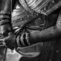 A black and white shot focusing on the bride's hands and the rich texture of her silk saree. The monochrome tones add a timeless, classic feel to the image.