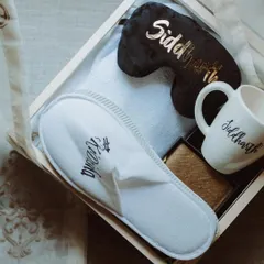 A personalized welcome kit for guests at a destination wedding. Including custom slippers, a mug, and an eye mask, these thoughtful gifts ensure guests feel comfortable and cared for from the moment they arrive.