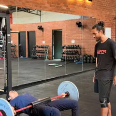 The coach-to-member ratio is key. Here you can see our coaches providing on-the-floor assistance, correcting form during weighted sit-ups and hip thrusts, and ensuring every member gets the attention they need.