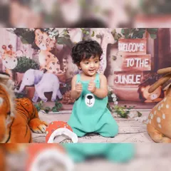 A close-up of a child enjoying the Jungle Safari setup. The decor includes a printed backdrop with jungle animals, wooden crates with "Welcome to the Jungle" signs, and plush animal toys.