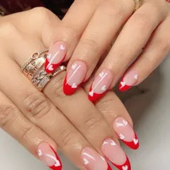 This Valentine's-themed set features a vibrant red French tip on almond-shaped nails, with tiny hand-painted white hearts scattered across for a touch of romance.