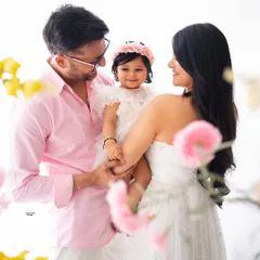 A perfect family of three. This portrait, framed by soft flowers, captures the love and happiness of the new parents with their adorable baby girl.