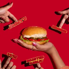 This vibrant shot of a burger against a bold red background is designed to grab attention. The composition with multiple hands pointing at the burger makes it look incredibly desirable.