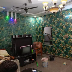 A living room fully wrapped in a green and gold leaf-patterned wallpaper. This creates a rich, luxurious feel, and I ensure the pattern matches perfectly at every corner.