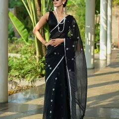 A chic and modern look for the brand AVA India, featured in Sananda. The model wears a black handloom saree with sunglasses, giving a contemporary twist to traditional wear.