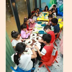 The best part of any party is sharing a meal with friends. Here, a group of children are gathered at our colorful tables, happily eating cake and snacks during an under the sea themed birthday celebration.