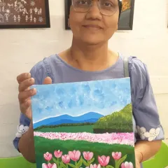 Anju proudly holds her finished painting of a field of tulips. Her journey is an inspiration, showing the healing power of art.