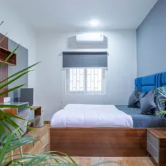 A completed bedroom in the Housr Nest co-living project in Koramangala. This real-world example highlights our focus on creating functional and comfortable living spaces, featuring a custom-built bed with a vibrant blue headboard, a compact study desk, and efficient use of space.