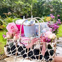 This stunning macrame basket is filled with goodies for both mom and baby, including personalized sippers, a baby bib, and fresh flowers, making it a perfect baby shower gift.
