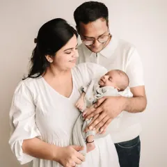 The new family of three, with mom and dad looking down at their precious newborn baby.