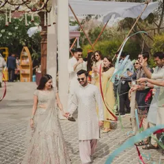 A joyful ribbon entry for the couple at their 'Artisan's Studio' Mehendi, with friends and family creating a colorful, welcoming pathway.
