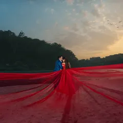 An absolutely breathtaking wide shot where the flowing red gown seems to merge with the river and the twilight sky. This is how we use dramatic composition to create unforgettable, large-scale pre-wedding portraits.