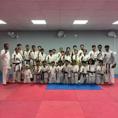Students of all ages and belt levels, from white to black, posing together after their belt grading exam.