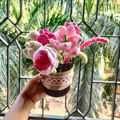 A beautiful basket filled with an assortment of pink and white crochet flowers. This arrangement includes roses, tulips, and lilies for a lush, full look.