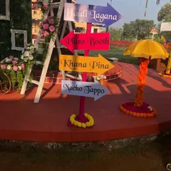 We love adding fun, personal touches to your event. This colorful directional signpost points guests to all the important spots: 'Haldi Lagana', 'Photo Booth', 'Khana Pina', and of course, 'Nacho Tappo'.