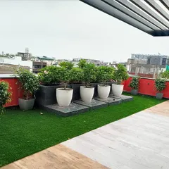 This rooftop design uses a clean, modern aesthetic. I installed artificial turf alongside a light-colored wood-look deck and arranged a series of ficus trees in minimalist white planters on a raised platform.